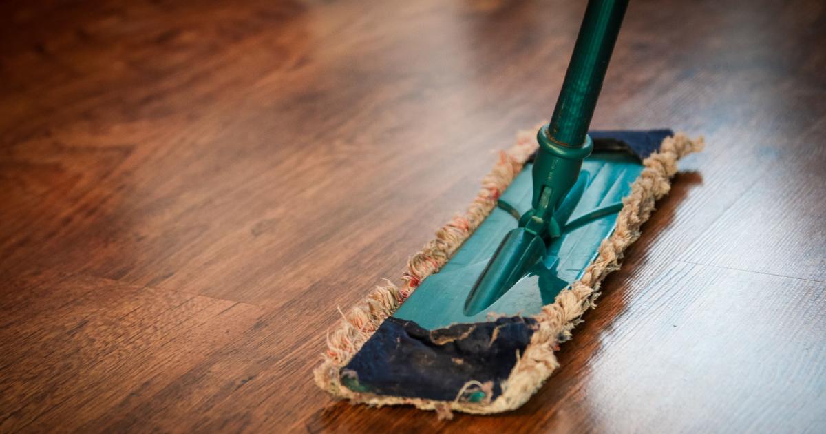Osoba stříkající speciální čistič na skvrnu na dřevěné podlaze