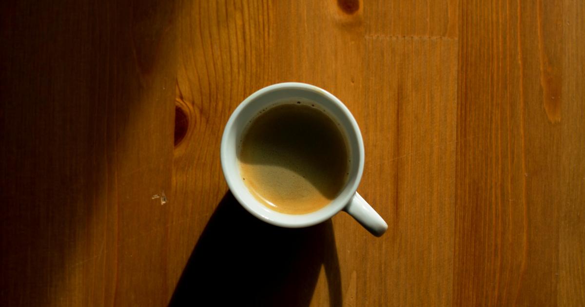 Kouřící hrnek kávy vedle moderního překapávače na čisté lince