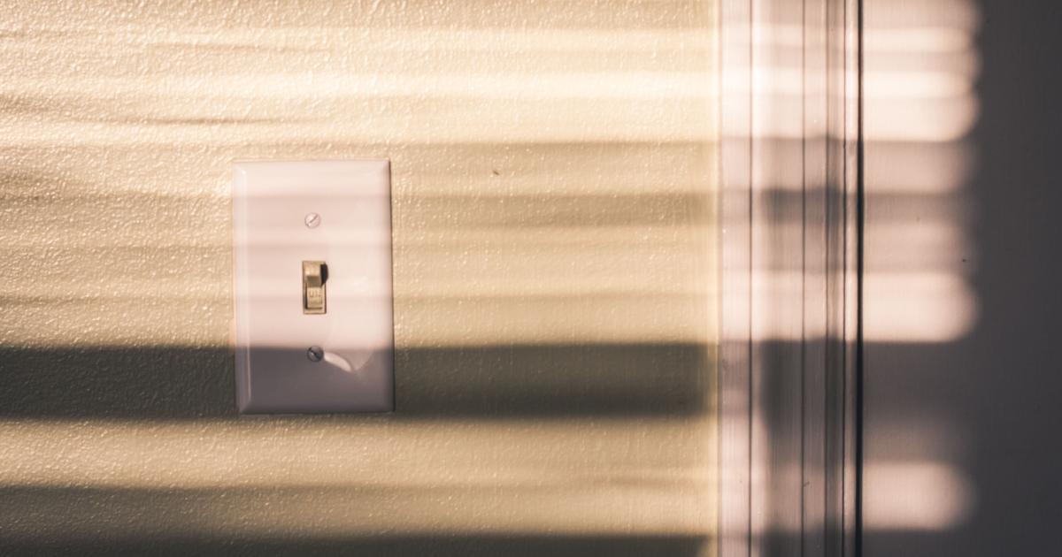 Detailní záběr na lehce zašpiněný bílý vypínač na neutrální stěně