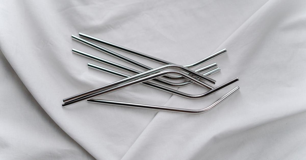 Detailní záběr osoby čistící opakovaně použitelné plastové brčko tenkým drátěným kartáčkem