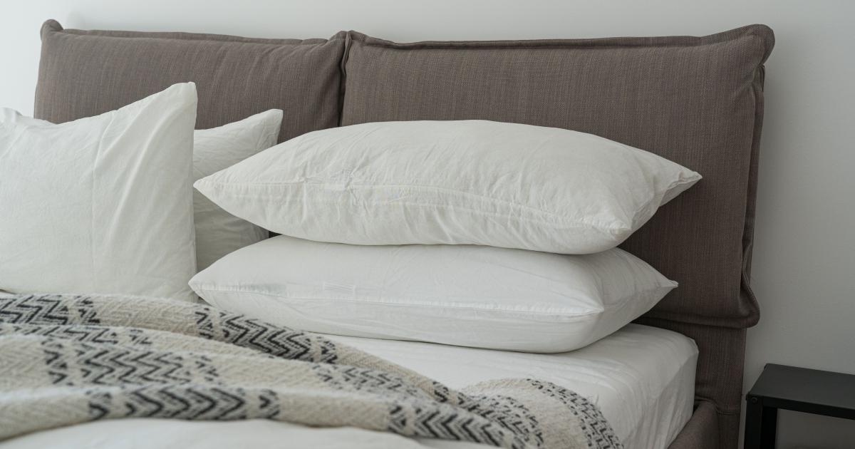 Osoba držící silný ergonomický polštář z paměťové pěny s bílým potahem