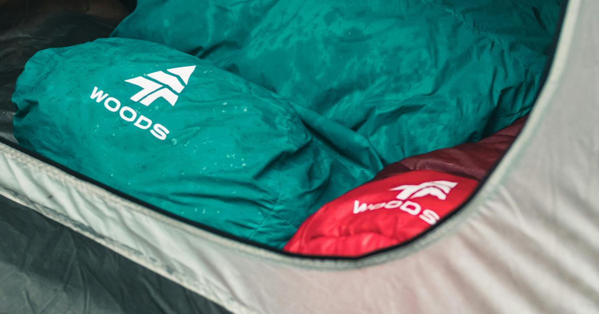 Nadýchaný modrý spacák rozprostřený na čisté dřevěné podlaze