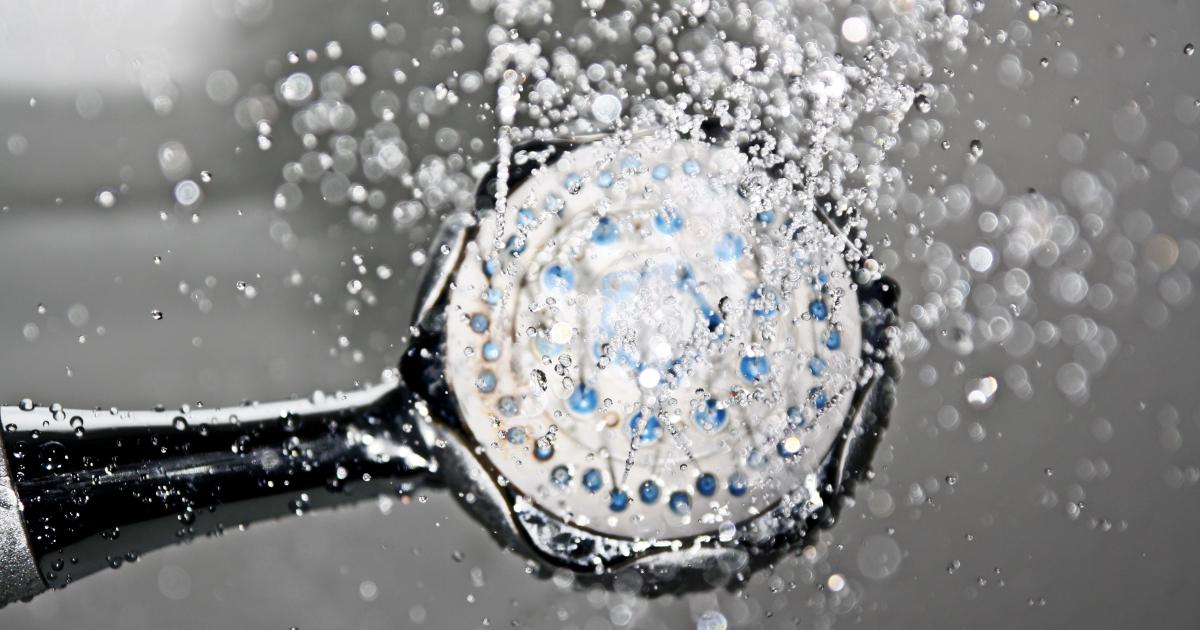 Ruka odšroubovávající chromovaný sprchový filtr z trubky