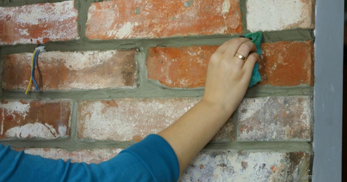 Ruce drhnoucí spáry mezi cihlami pomocí pevného nylonového kartáčku