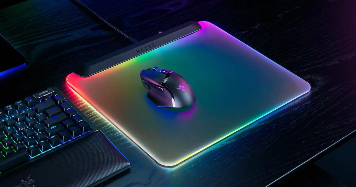 Detailní záběr na vlhký hadřík z mikrovlákna otírající tmavou herní podložku se svítícími RGB okraji