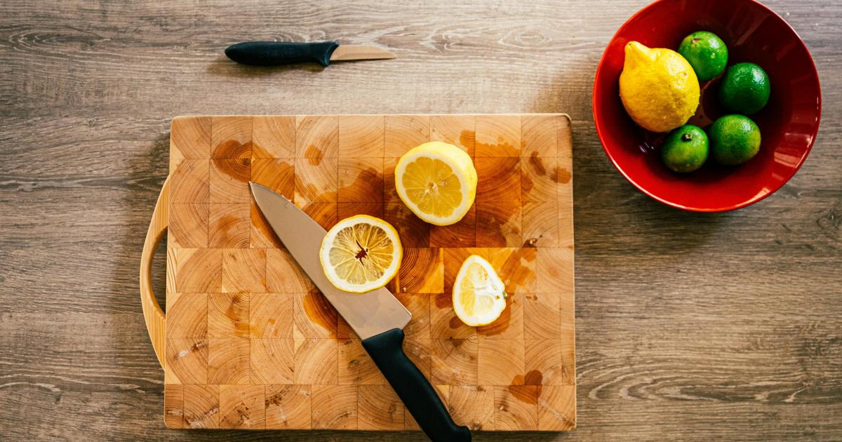 Drhnutí dřevěného krájecího prkénka polovinou citronu a hrubou solí