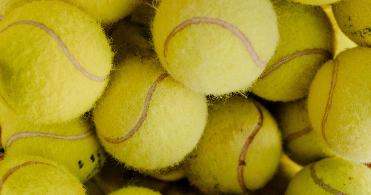 Tenisové míčky položené na hromadě čistého prádla v bubnu sušičky